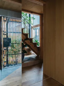 A modern interior featuring a wooden staircase with a glass railing, adjacent to a garden view.