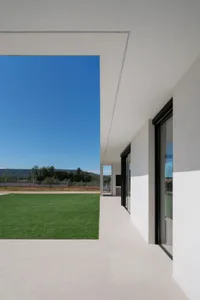 Modern minimalist house exterior with white walls and a green lawn.