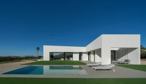 Modern residential exterior with white concrete walls and a swimming pool.