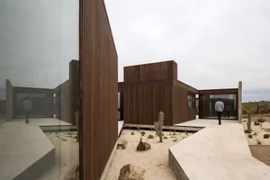 Minimalist exterior with wooden panels, glass windows, and concrete floors and pavement.
