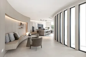 Modern open-plan living room and dining area with minimalist furniture and concrete floor tiles.