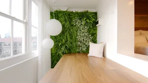 Modern living space featuring a vertical garden wall with green plants, white lighting, and wooden flooring.