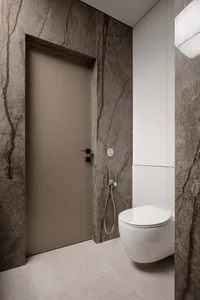 Modern bathroom featuring a wall adorned with marble tiles, a sleek white toilet, and minimalist fixtures.