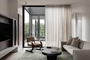 Modern minimalist living room featuring textured cotton sofa, round coffee tables, and large curtains.