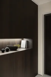 A modern cabinet made of dark wood with a shelf displaying decorative items, including a black bowl, a black spherical orname