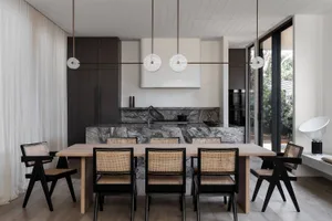 Modern residential kitchen featuring luxurious marble countertops and backsplash, with dark wooden cabinets and a sleek, mini