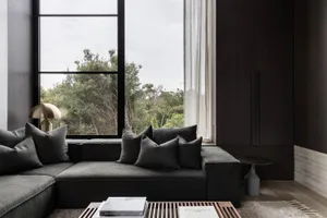 Modern living room featuring a black sofa with grey pillows.