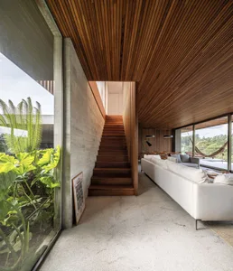 A modern living room featuring wooden elements and large windows with greenery outside.