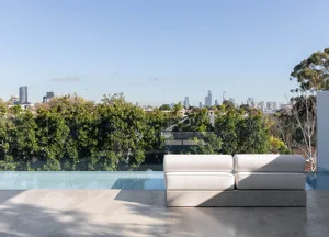 Modern outdoor lounge area with concrete seating and infinity pool overlooking cityscape.