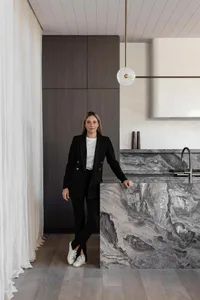 A modern residential interior featuring a kitchen with marble countertops and dark wooden cabinets.