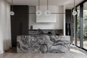 A modern residential kitchen featuring marble countertops and flooring.