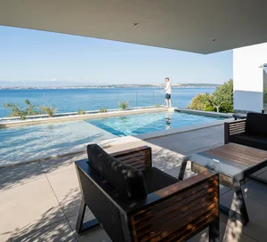 Modern residential pool deck featuring concrete, glass, metal, and wood materials.