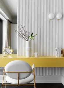 Modern home office with yellow desk and white chair, featuring a white vase with flowers and a lamp on the desk.