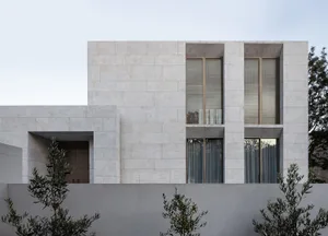 A modern residential building with a white marble exterior and large windows.