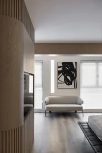 Modern minimalist living room with light-colored sofa, black and white abstract artwork, and wooden paneling.