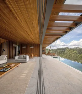 Modern, open-plan residential space featuring a concrete floor and large windows overlooking the natural landscape.