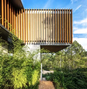 Modern residential exterior featuring wooden slats, stone, and concrete materials.