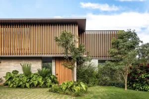 Modern residential home exterior featuring wooden slats, concrete base, and glass windows.