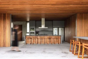 Modern kitchen with wooden cabinets, countertops, and stools.