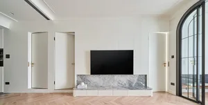 Modern minimalist living room with a marble wall and wooden flooring.