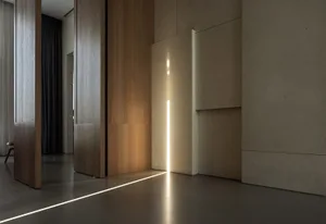 Interior of a modern minimalist living room featuring wooden paneling, concrete surfaces, and a linear light installation.