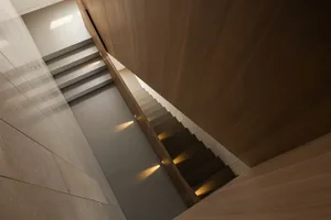 Modern minimalist staircase with wooden treads and illuminated steps, showcasing sleek and elegant design
