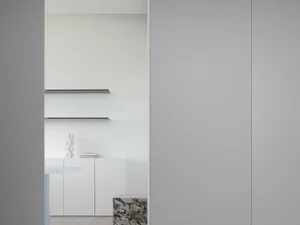Modern, minimalist white kitchen with floating shelves and cabinets.