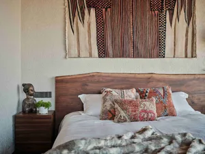 A bedroom featuring a wooden headboard, bohemian textiles, and a decorative sculpture.