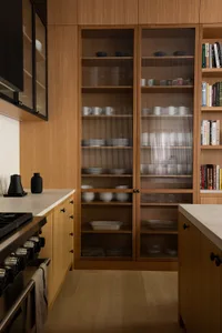 A modern kitchen featuring industrial design elements with wood and glass cabinets.