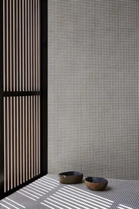 A minimalist bedroom with concrete flooring and a dark wood door.
