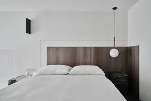 A modern bedroom featuring a wooden headboard with white bedding and pillows.