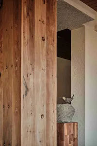 Modern interior space featuring textured wooden walls and a bird sculpture on a rock