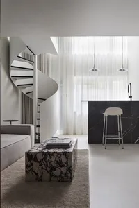 A modern living room featuring a spiral staircase, marble coffee table, and a sleek, minimalist design.
