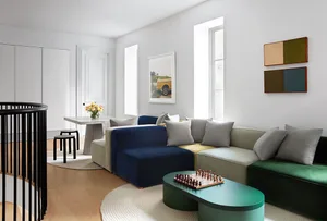 A modern living room featuring a sectional sofa with textured upholstery in shades of blue, beige, and green, placed on a rou