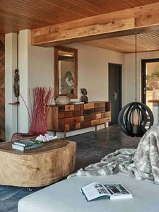A modern living room featuring wooden furniture, including a log coffee table, a rustic sideboard, and a plush blanket.