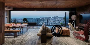 Modern living room with marble floor, sofas, wooden tables, and balcony overlooking a cityscape