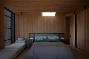 A minimalist bedroom with wooden paneling, a large bed, and a window with wooden blinds.