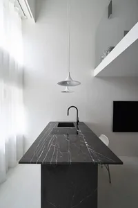 Modern minimalist kitchen with black marble countertop and white pendant lights.