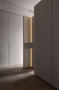 Modern minimalist entrance with concrete flooring and warm light strip along the wall.