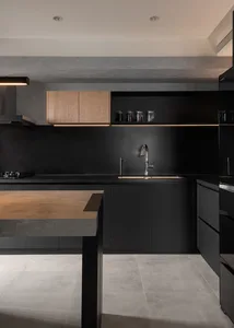 A modern minimalist kitchen with black cabinetry and metallic elements.