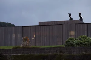 Modern residential exterior with metal cladding and illuminated windows.