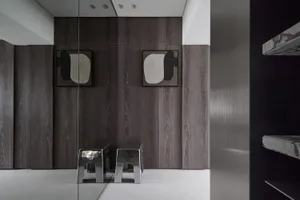 Minimalist interior with metal stools, wooden panels, and abstract artwork