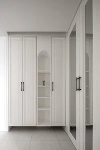 A minimalist white closet with sleek black handles and a small decorative object on the shelf
