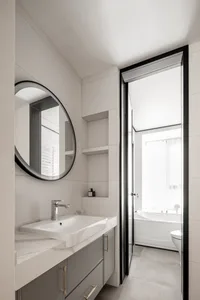 Modern, minimalist bathroom featuring sleek ceramic tiles, a floating vanity with a white countertop, and a mirror above the 
