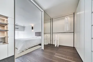 Modern bathroom with white walls, wood flooring, and minimalist design.