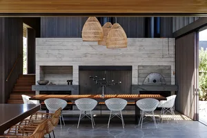 A modern living and dining room with concrete walls and a large table surrounded by white chairs.