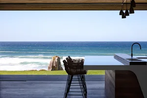 Modern kitchen with ocean view, featuring wood materials and sleek design.