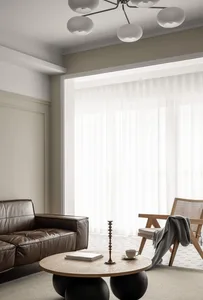 A modern living room featuring a brown leather sofa, wooden coffee table with a candle holder and coffee cup, and a wooden ar