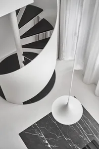 Minimalist design featuring a white concrete spiral staircase with a white floor lamp.