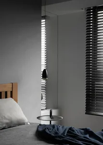 A modern minimalist bedroom with monochrome color palette, featuring a bed with a wooden headboard, gray bedding, a dark meta